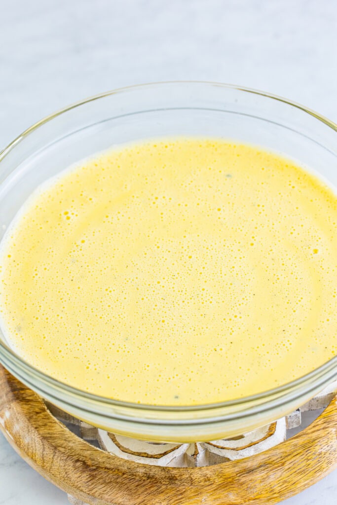 whisked creme brulee custard mixture in a glass bowl before baking