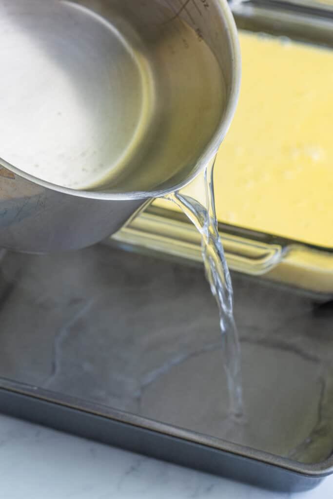 creme brulee custard poured into a glass baking dish set inside a water bath