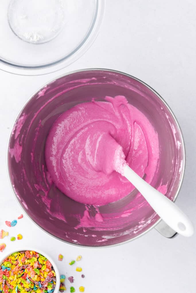 Pink macaron batter partially mixed during the macaronage process in a stand mixer bowl