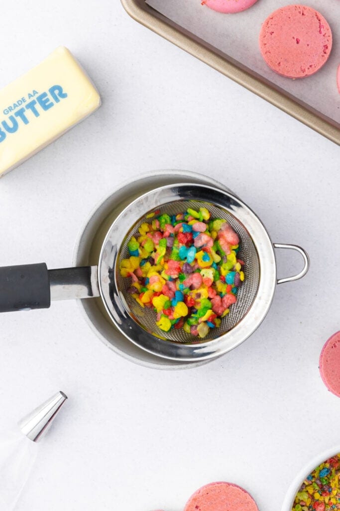 Fruity Pebbles cereal draining in a mesh strainer over a bowl to make cereal milk