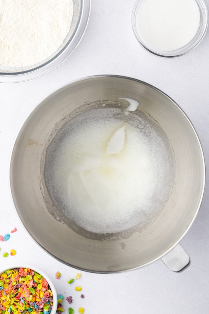 Foamy egg whites beginning to whip in a stand mixer bowl