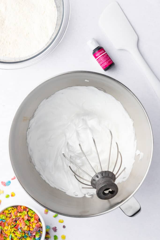 Stiff peak meringue in a stand mixer bowl with a whisk attachment lifted