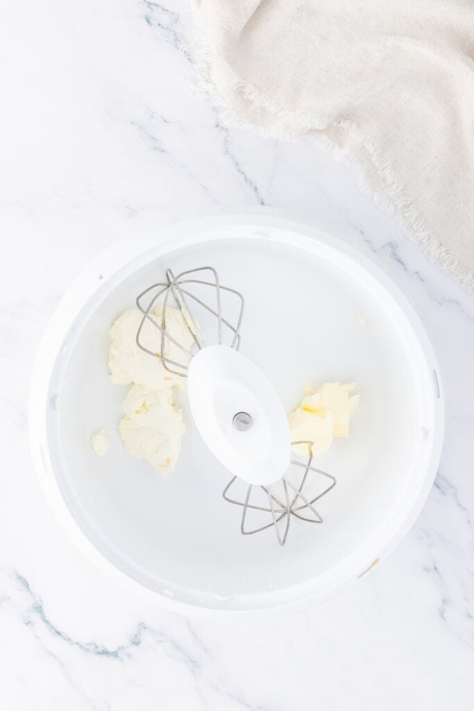 Butter and cream cheese in a mixing bowl with beaters attached, ready to be whipped for the truffle filling.