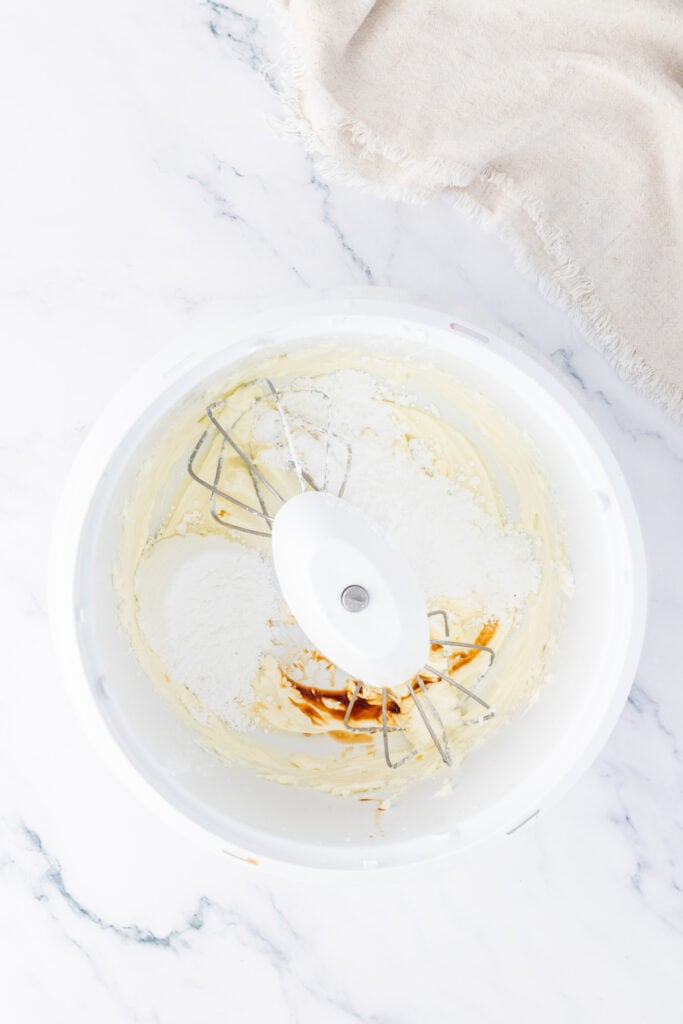 Mixing bowl with powdered sugar and butter being combined to make the frosting for pink Valentine truffles.