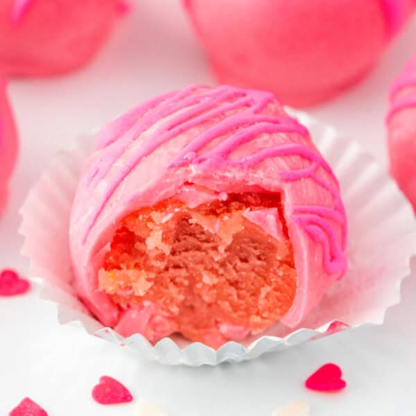Square-format image of pink Valentine truffles with smooth coating and drizzle.