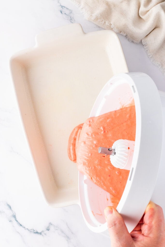 Strawberry cake batter being poured into a baking pan