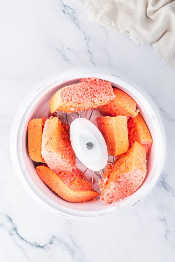 Strawberry cake broken into pieces in a mixing bowl for making cake truffles