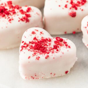 Close-up of a single strawberries and cream truffle heart coated in white candy and topped with crushed freeze-dried strawberries
