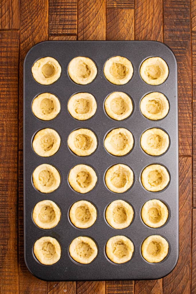 Baked sugar cookie cups pressed in a mini muffin pan showing the hollow centers
