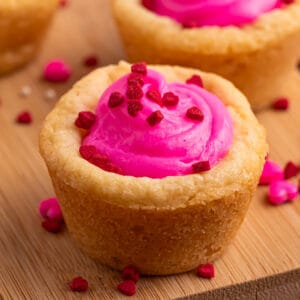 Square image of a Valentine sugar cookie cup with pink frosting and red heart sprinkles