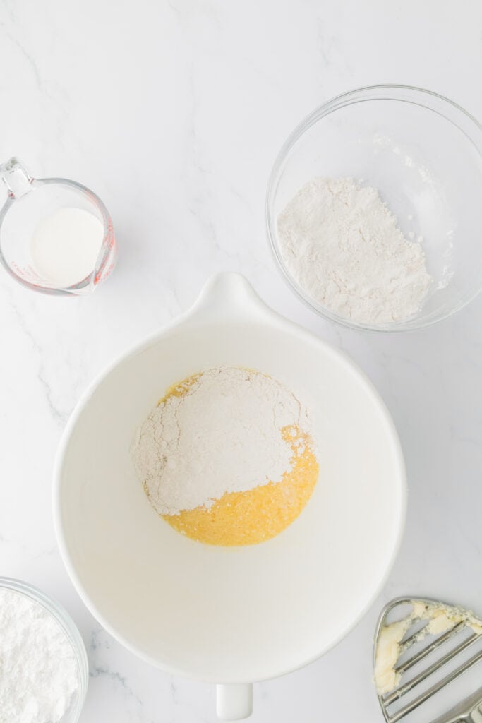 Flour mixture added on top of wet cake batter ingredients in a mixing bowl