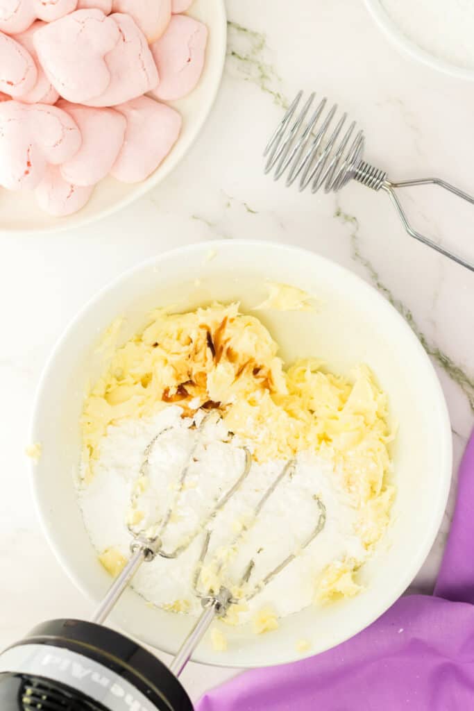 powdered sugar and butter being mixed together with an electric hand mixer