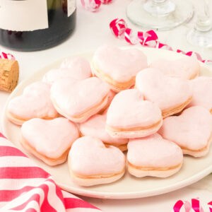 finished heart shaped Valentine macarons stacked on a plate with festive pink accents