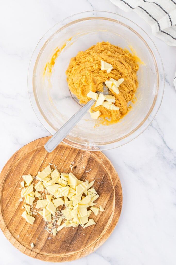 Blondie batter mixed with chopped white chocolate on a wooden board