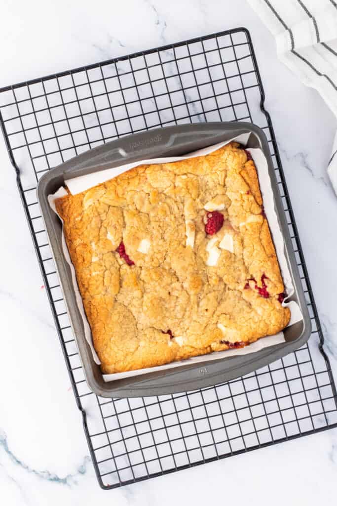 Baked white chocolate raspberry blondies cooling in the pan on a wire rack