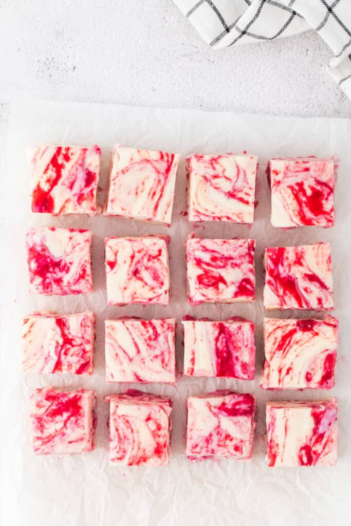 White chocolate raspberry fudge cut into uniform squares and arranged on parchment paper