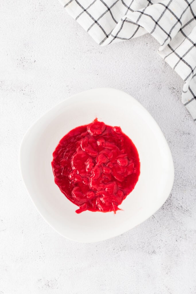 Strained raspberry puree collected in a white bowl