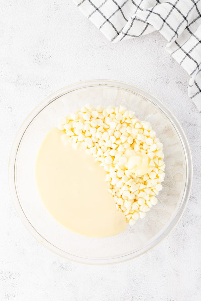 White chocolate chips and sweetened condensed milk in a glass bowl