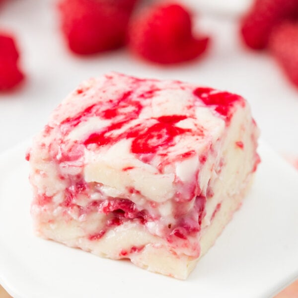 Close-up of a single square of white chocolate raspberry fudge with smooth white chocolate and raspberry streaks