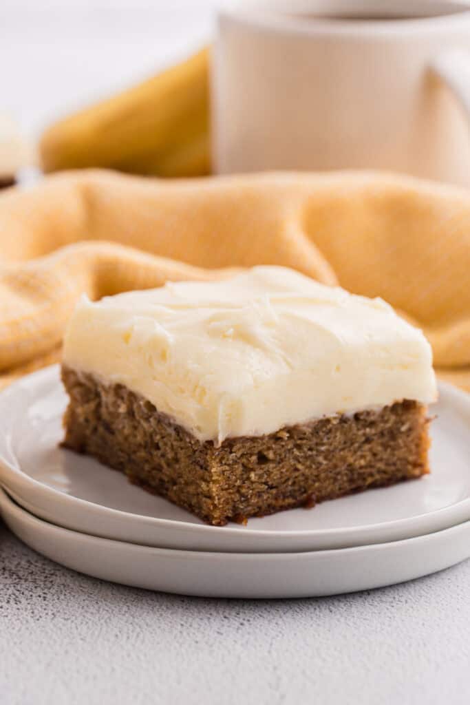 Single banana brownie square with cream cheese frosting on a white plate
