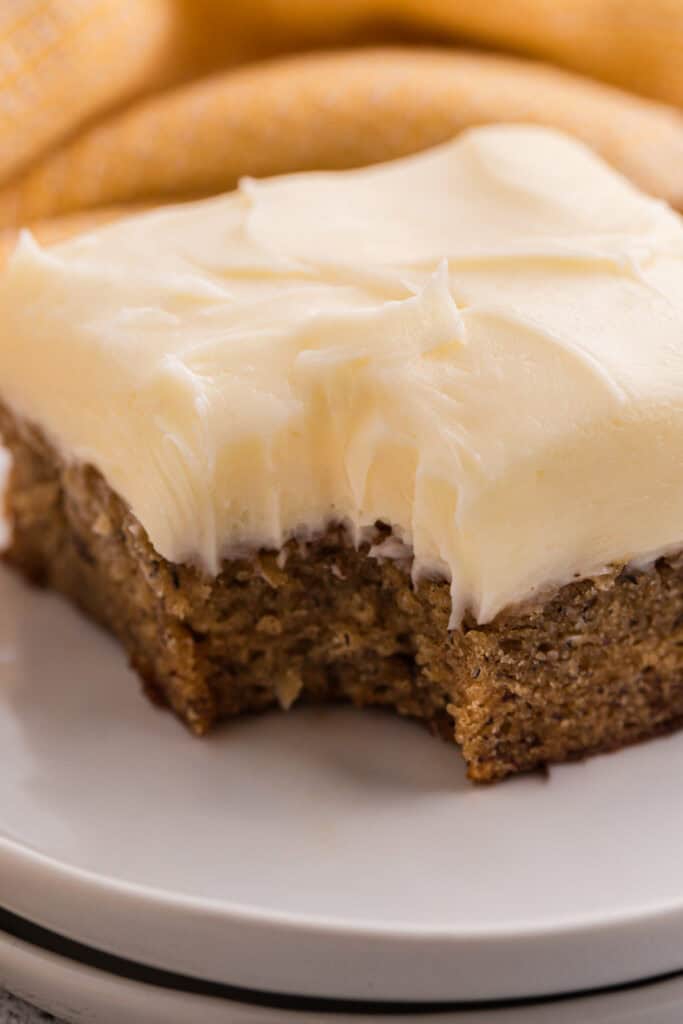 Close up side view of a banana brownie square with cream cheese frosting showing the crumb texture