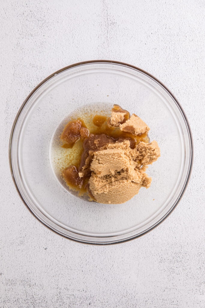Glass mixing bowl with melted oil and packed brown sugar