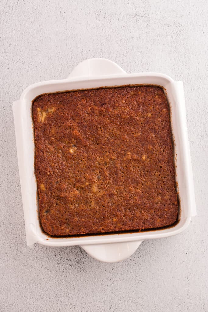 Baked banana brownie layer in square pan lined with parchment paper