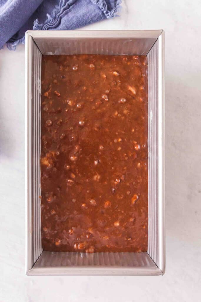 Brownie banana bread batter poured into a greased loaf pan before baking.