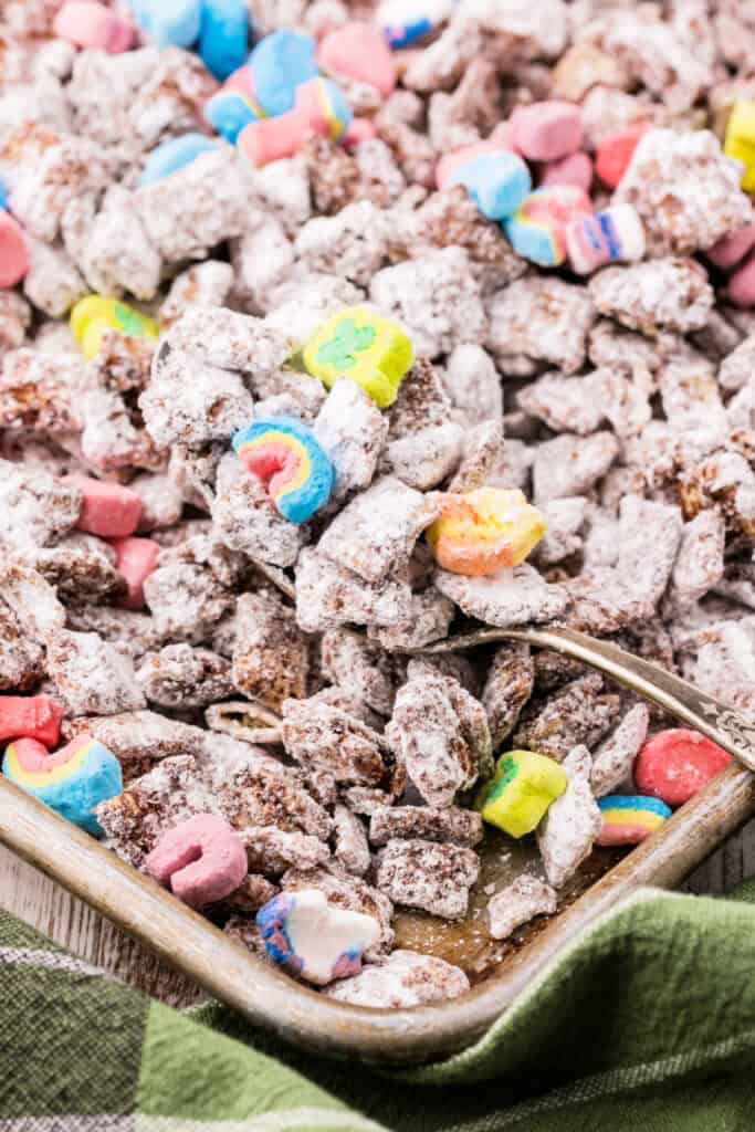 Close up of powdered sugar coated Chex cereal with colorful marshmallows in a metal baking pan.