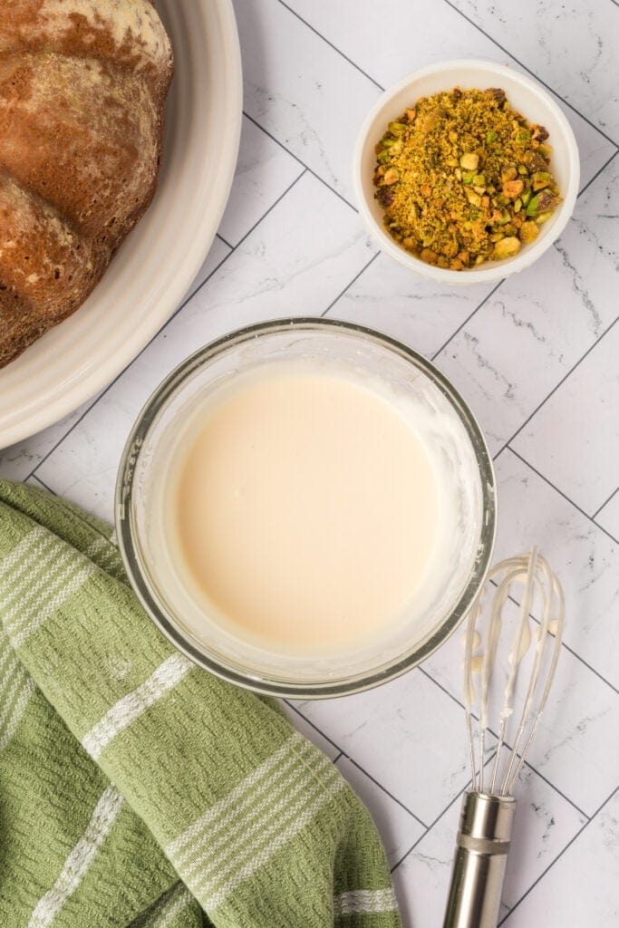 smooth glaze mixture in a glass bowl with whisk beside it