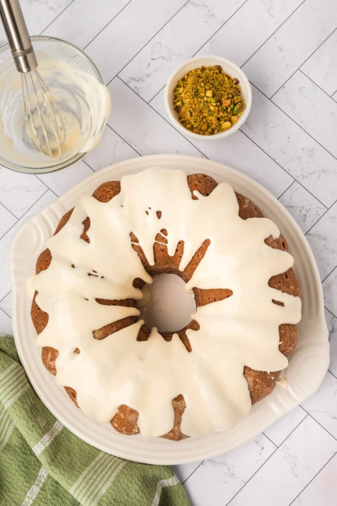 pistachio bundt cake with glaze poured over the top on a serving plate