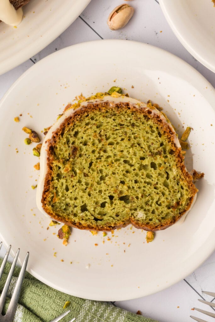 single slice of pistachio bundt cake on a plate with pistachio crumbs