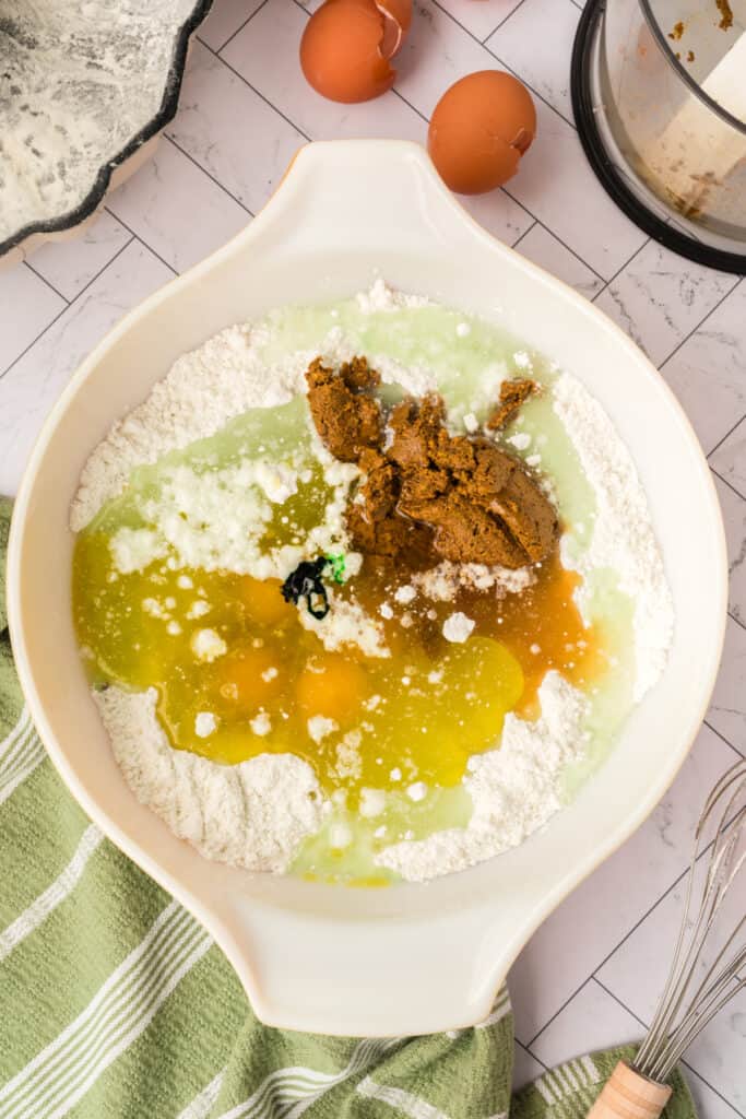 wet ingredients and pistachio paste added to dry ingredients in a mixing bowl