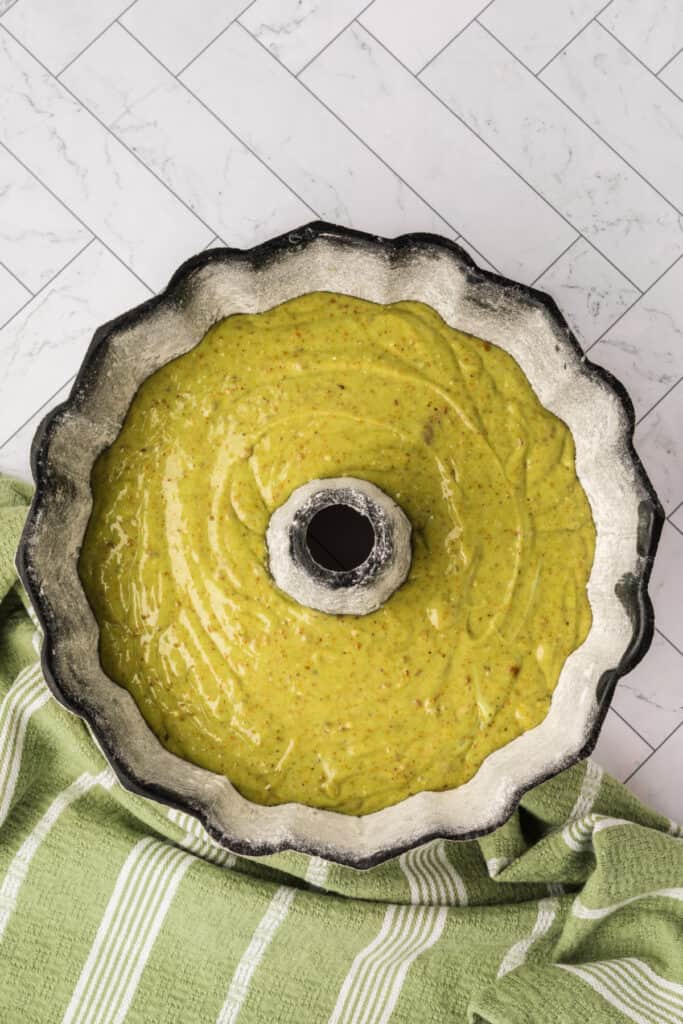 pistachio cake batter poured into a floured bundt pan