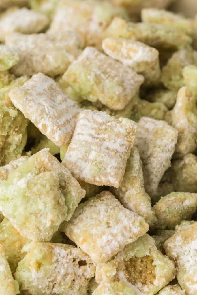 Extreme close up of pistachio muddy buddies showing powdered sugar coating and green pistachio mixture on Chex cereal