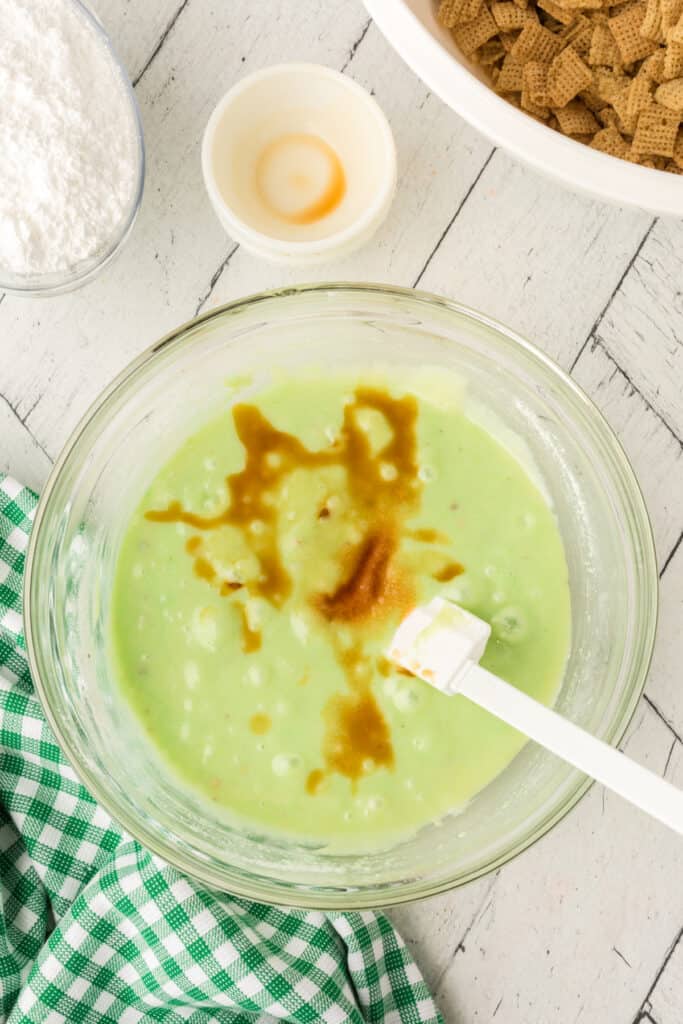Vanilla extract poured into green pistachio mixture in glass bowl