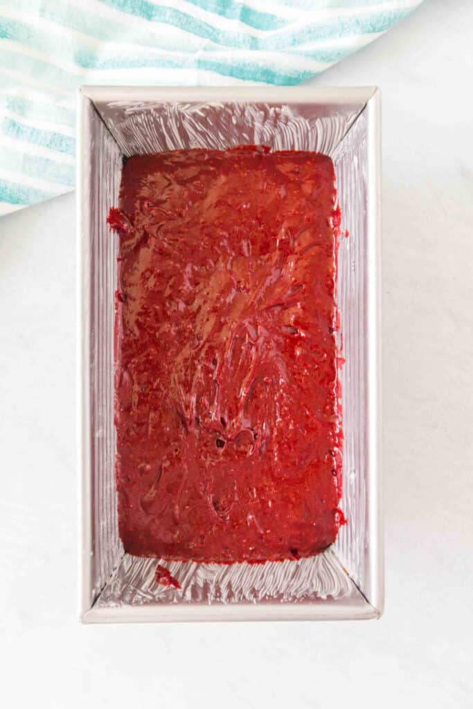 Red velvet batter spread evenly inside a greased 8 x 4-inch loaf pan.