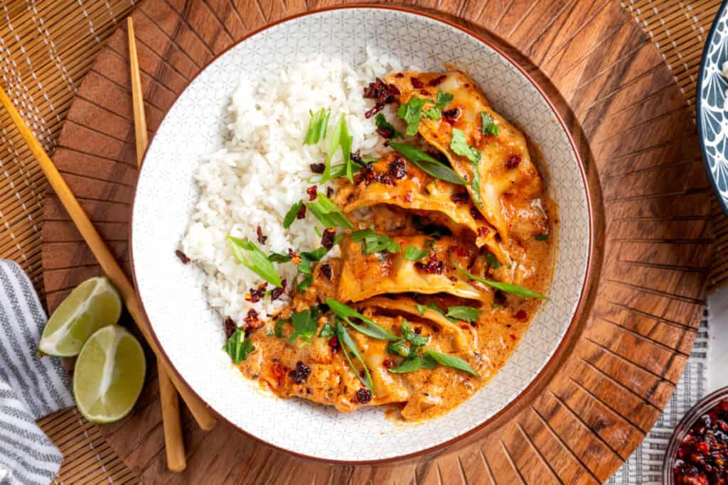 serving of baked curry dumplings with rice topped with cilantro, green onions, and chili crunch
