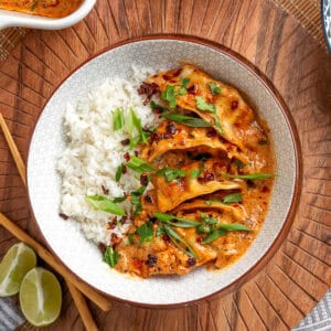 plated baked curry dumplings with rice topped with green onions, cilantro, and chili crunch