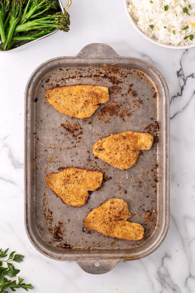 baked flounder fillets on a baking sheet with browned breadcrumb coating