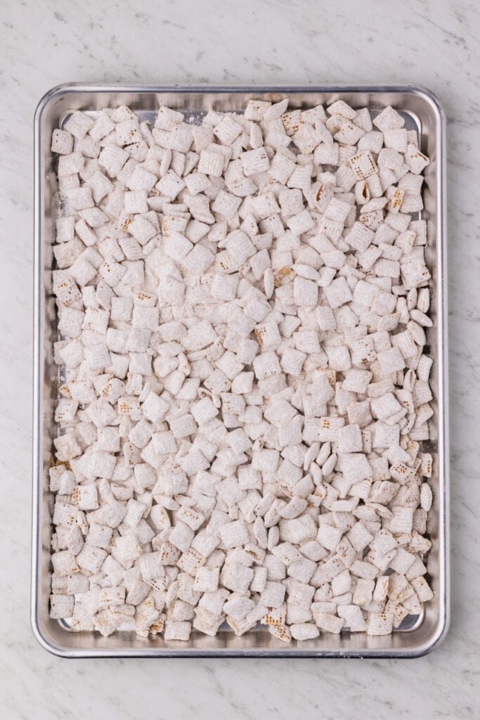 carrot cake muddy buddies spread on a baking sheet to cool