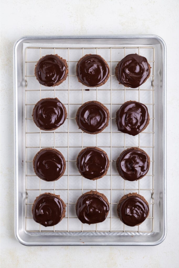 chocolate cookies topped with glossy chocolate ganache on a wire rack