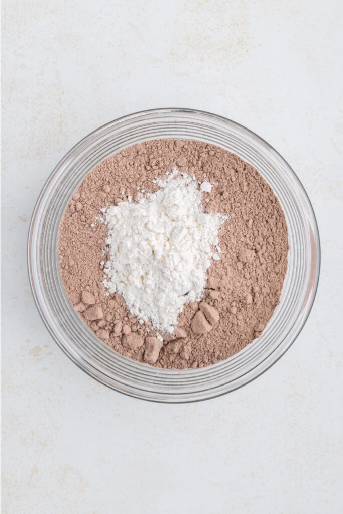 glass bowl filled with chocolate brownie mix and a mound of white flour in the center