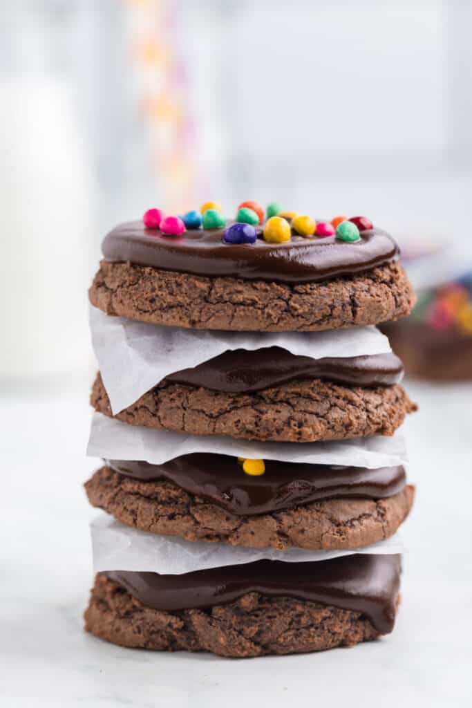 stack of chocolate cookies with ganache layers and parchment paper between cookies