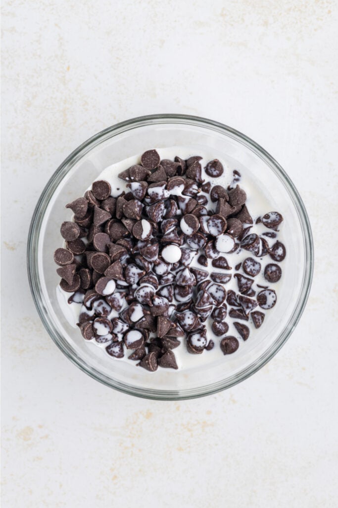 chocolate chips and heavy cream in a glass bowl before melting