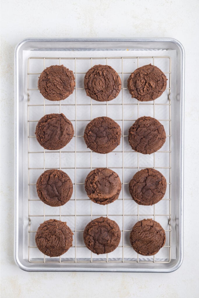 baked chocolate cookies cooling on a wire rack over a baking sheet