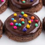 close up of a chocolate cookie with glossy ganache and rainbow candy-coated chips on top