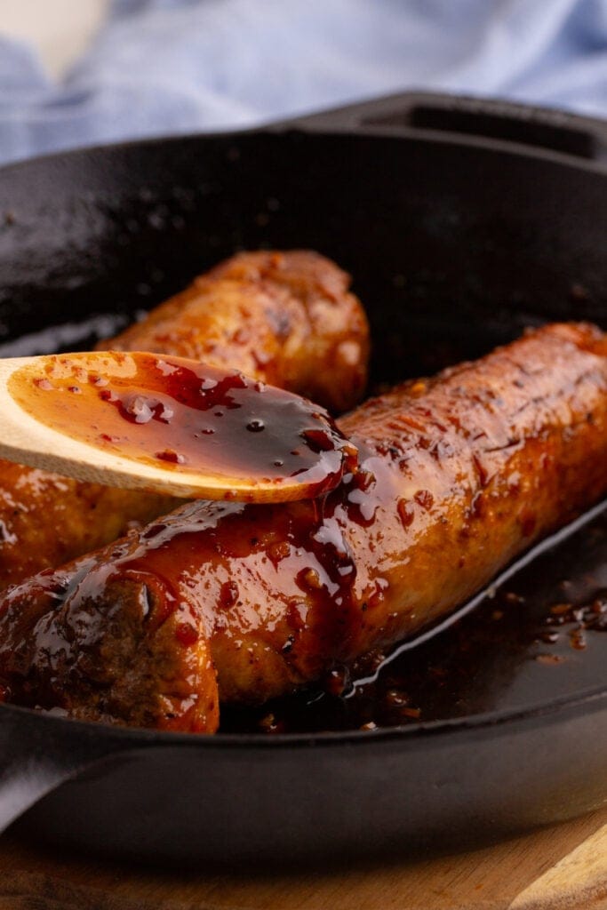 Close-up of honey garlic glaze spooned over pork tenderloin in a cast iron skillet.