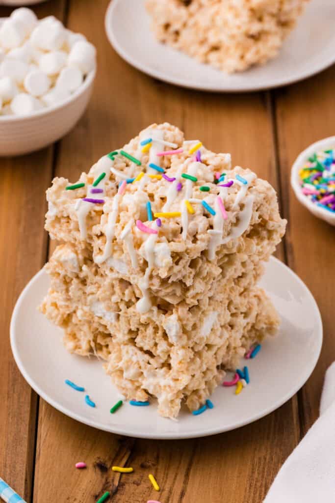 stack of lemon rice crispy treats topped with white drizzle and colorful sprinkles on a plate