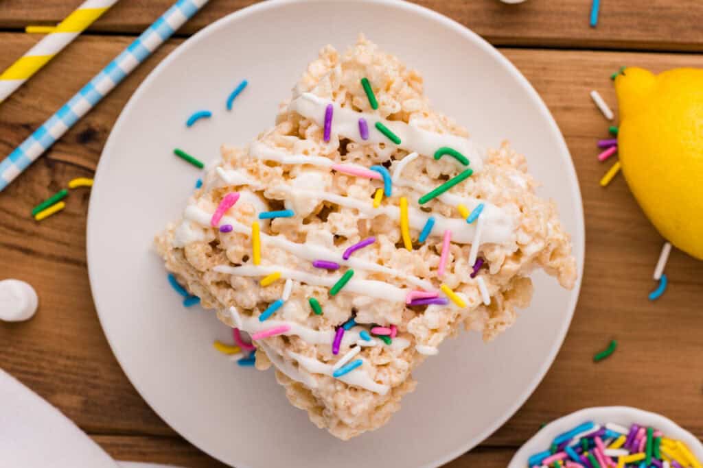 single lemon rice crispy treat topped with white drizzle and colorful sprinkles on a plate